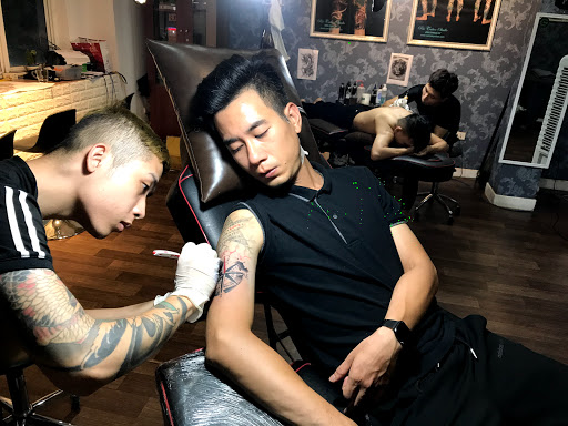 Thợ xăm chuyên nghiệp đang thực hiện hình xăm nghệ thuật chi tiết trên da khách hàng với thiết bị hiện đại
